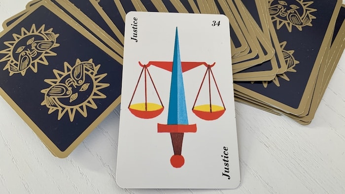 Carte Justice de l'Horoscope Belline avec une balance dorée sur fond bleu.