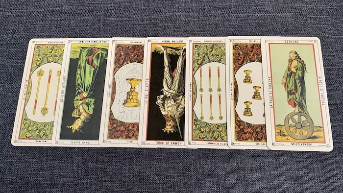 Sept cartes du Tarot Égyptien Oracle des Dames posées en ligne sur fond bleu, la plupart renversées, illustrant un tirage avec la méthode Etteilla