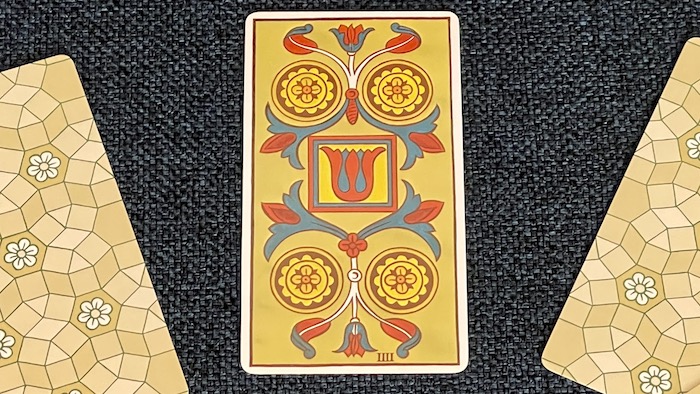 Carte du Quatre de Deniers montrant quatre pièces autour d'un motif central.