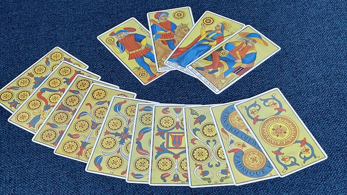 Ensemble des Deniers du Tarot de Marseille avec pièces et feuillages colorés.