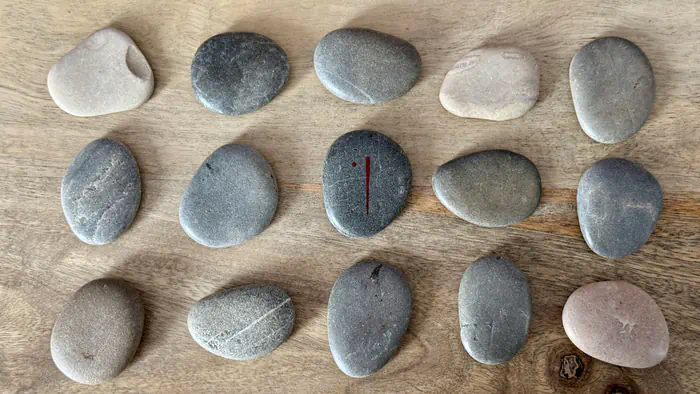 Rune Isa au centre avec son symbole gravé, entourée de pierres sacrées sur une table de consultation divinatoire.
