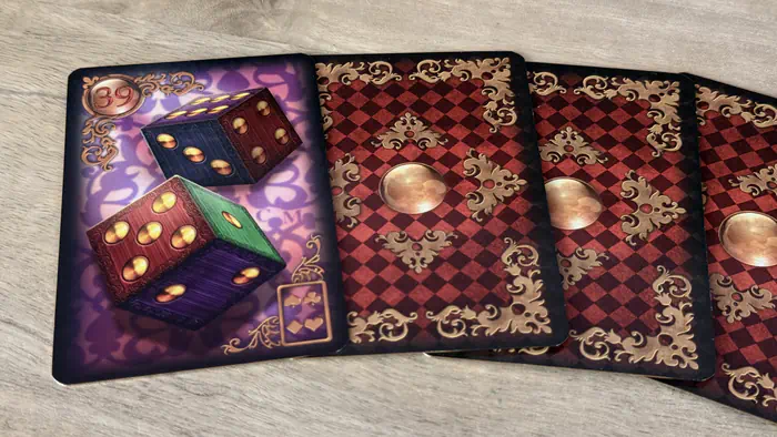 Carte Les Dés 39 Gilded Lenormand mettant en scène le hasard et le risque sur un fond de bois clair texturé.