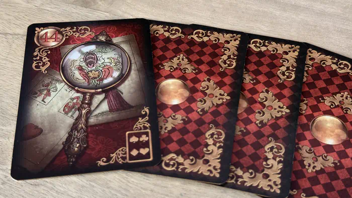 Carte La Loupe 44 Gilded Lenormand focalisant sur la recherche de détails et de vérité lors d'une lecture.