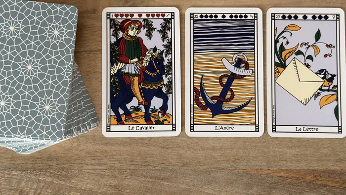 Tirage 3 cartes Petit Lenormand : Cavalier, Ancre et Lettre à côté du tas de cartes.