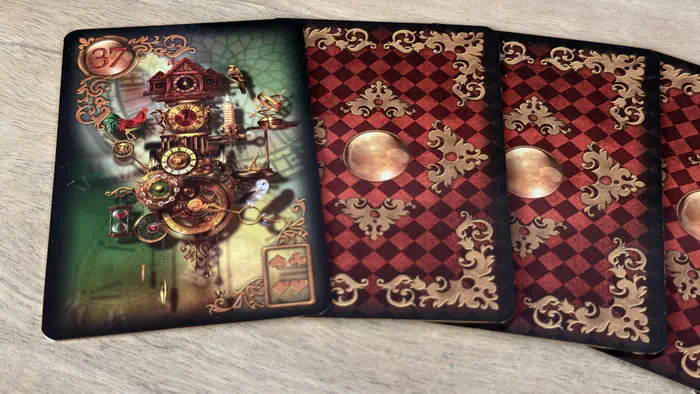 Carte Le Temps 37 Gilded Lenormand montrant une horloge complexe sur un étalement de cartes face cachée.